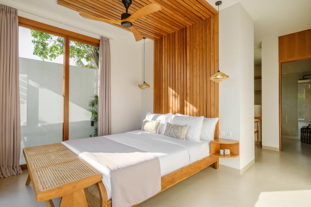 a bedroom with a large white bed and a window at Las Hermanas Villa by MAR Bali in Dalung