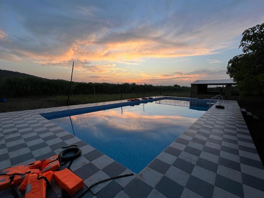 a swimming pool with a sunset in the background at Greenlife farm resort in Sasan Gir