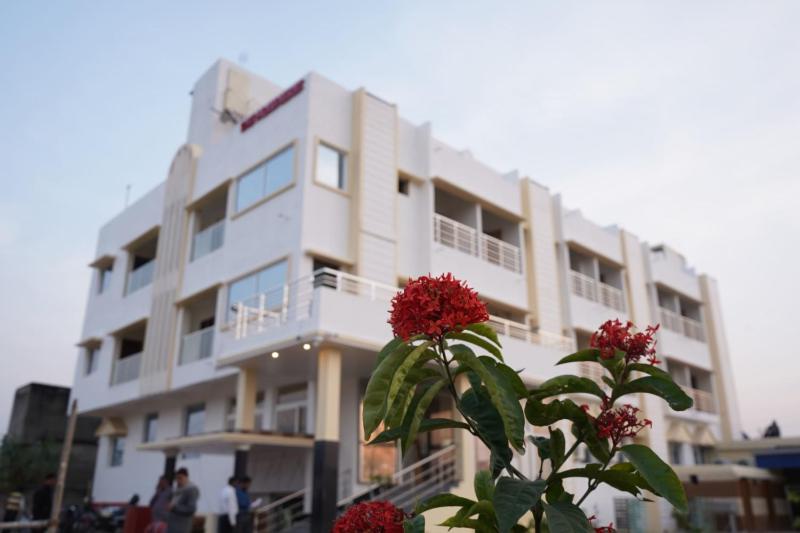 a white building with red flowers in front of it at Swet Palash Resort in Purulia