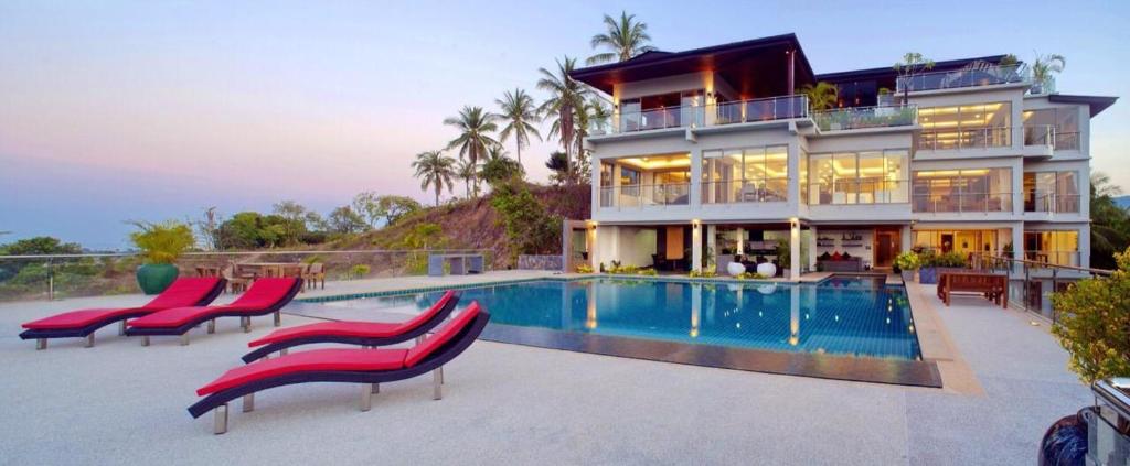 a house with a swimming pool and some red chairs at Yupa Penthouse in Amphoe Koh Samui