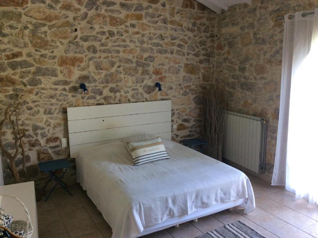 ein Schlafzimmer mit einem Bett und einer Steinmauer in der Unterkunft Authentique Mas avec piscine et pool house in Mouriès