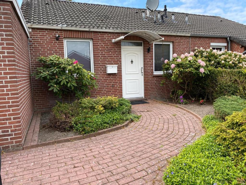 HageにあるFerienhaus Meerwehの白い扉とレンガ造りの私道のあるレンガ造りの家