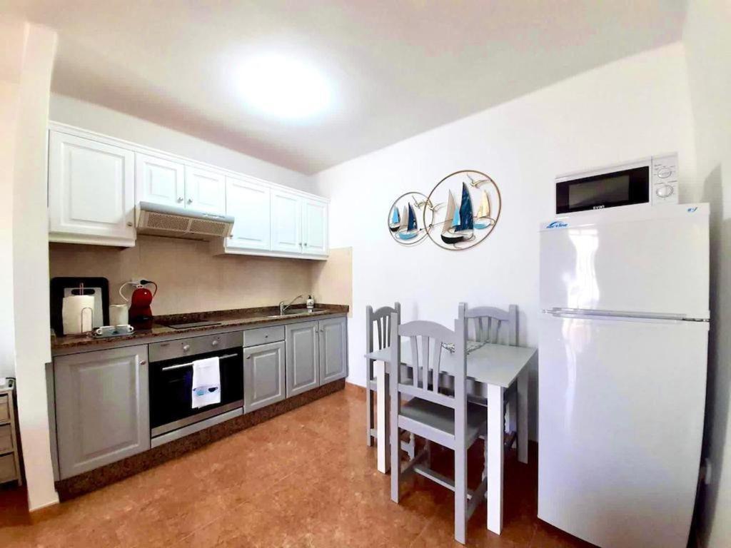 a kitchen with a white refrigerator and a table and chairs at Apartamento Lory-Puerto del Carmen in Puerto del Carmen