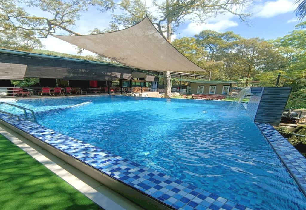 een groot zwembad met een tegelvloer en een gebouw bij Collection O 90858 Bentong Wellness Homestay Midland in Kampong Sungai Chendarawi