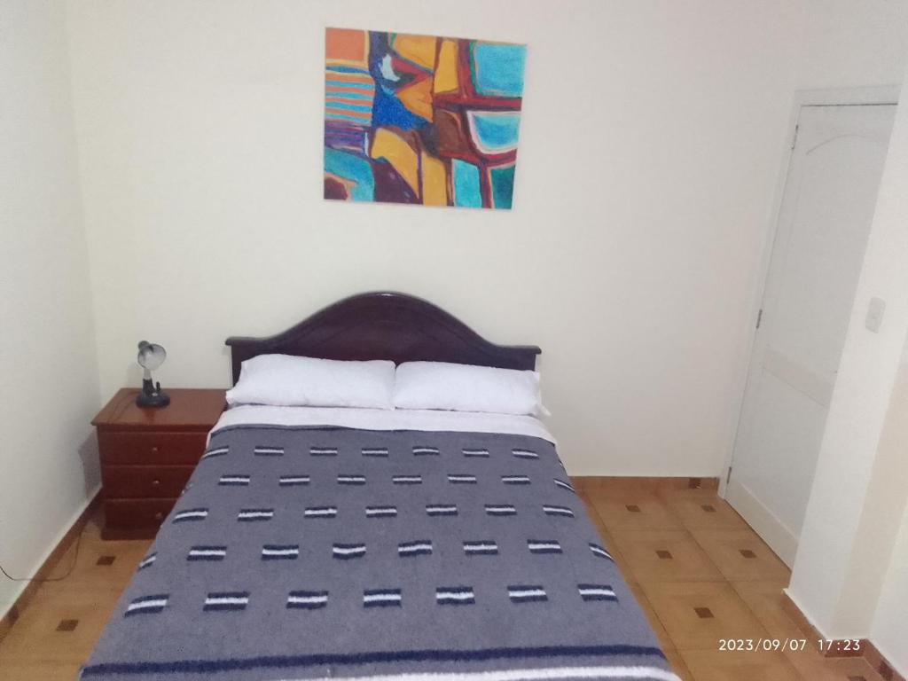 uma cama num quarto com uma pintura na parede em Apartamento en Vilcabamba em Vilcabamba