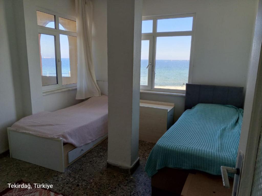 a bedroom with two beds and a window with the ocean at Sultanköy Apart in Marmaraereglisi