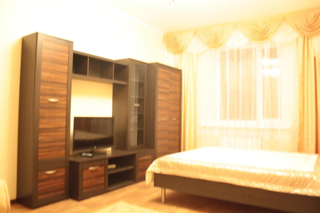 - une chambre avec un lit, une commode et une télévision dans l'établissement Уральск, à Uralsk