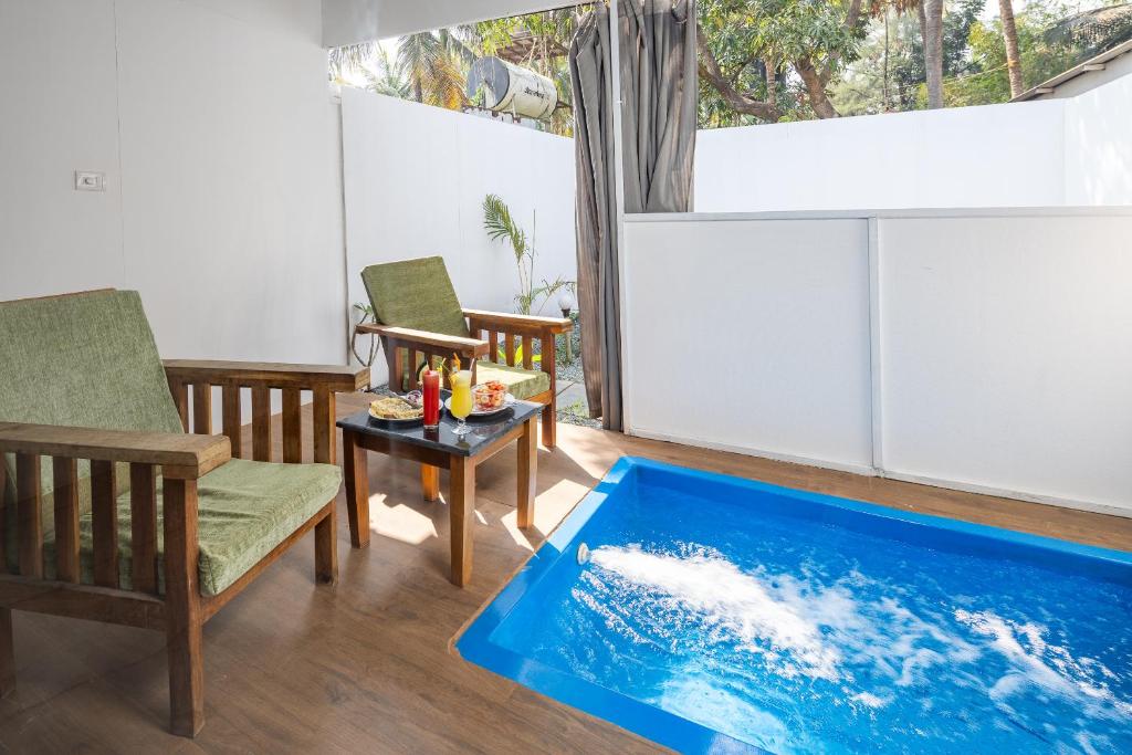 Crystall Goa Turquoise Edition في باتنيم: حوض استحمام في غرفة معيشة مع طاولة وكراسي