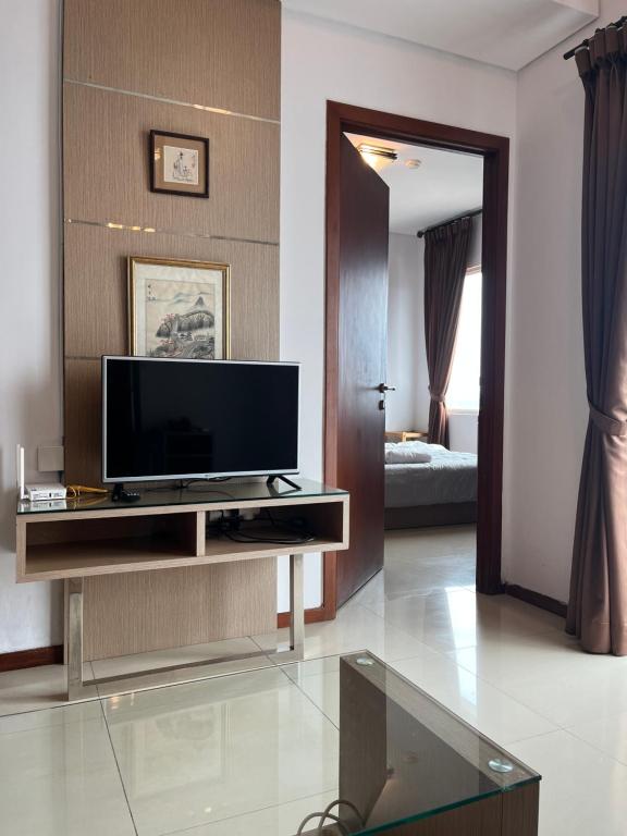 a living room with a flat screen tv on a entertainment center at Comfy 1BR At Central ( City View ) in Jakarta