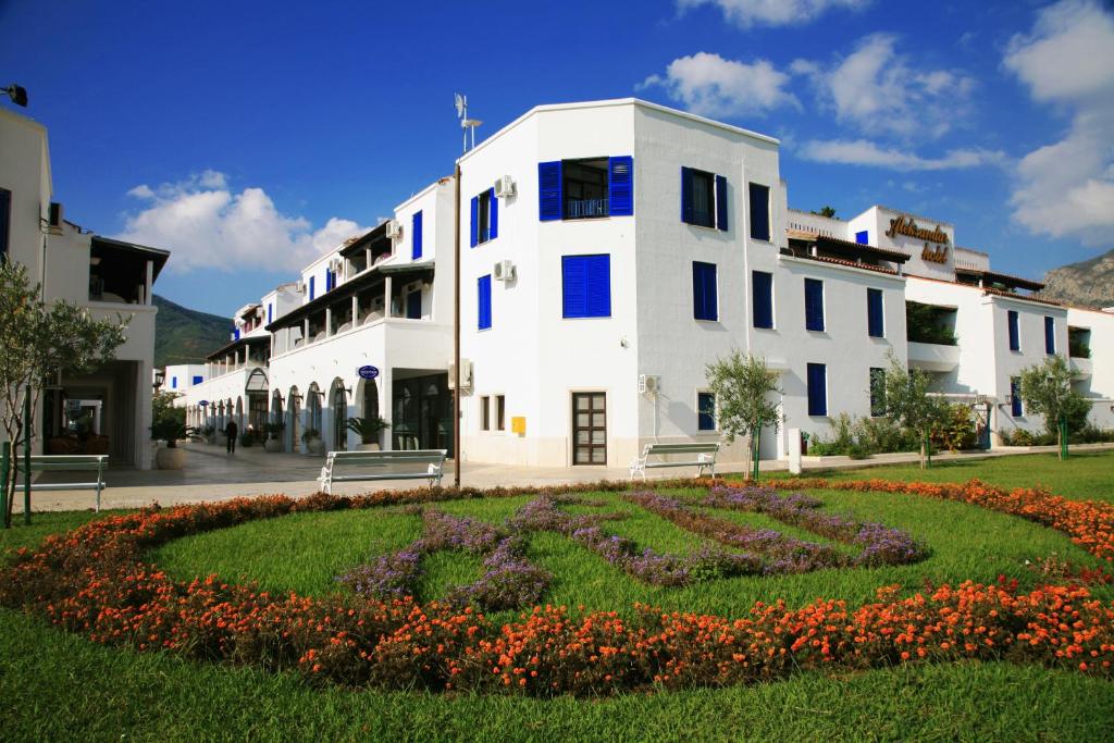 a large white building with a garden in front of it at Hotel Aleksandar in Budva