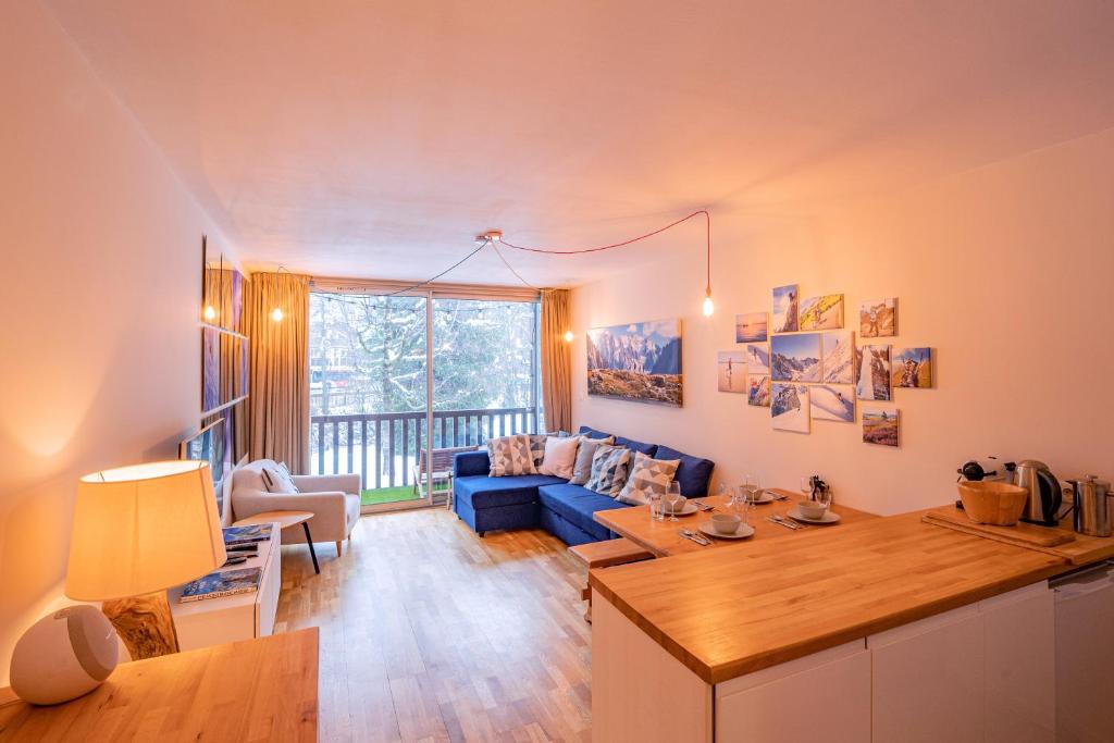 Apartment Arve في شامونيه مون بلان: غرفة معيشة مع أريكة زرقاء وطاولة