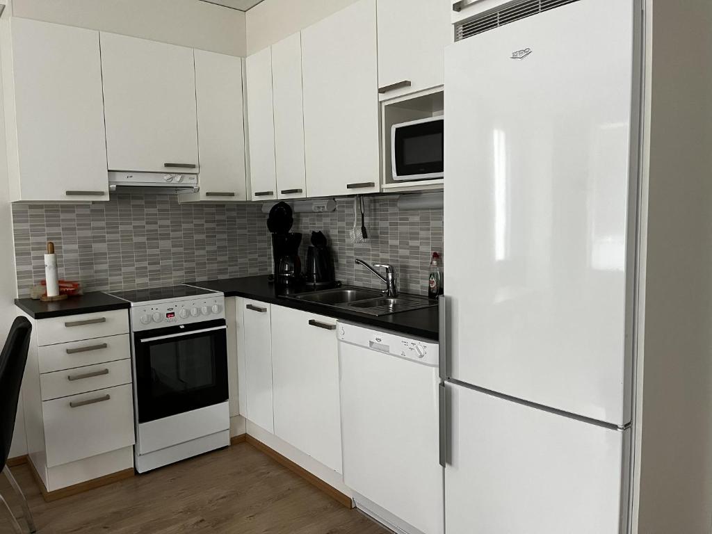 La cuisine est équipée de placards blancs et d'un réfrigérateur blanc. dans l'établissement Bästlandia Apartments with Sauna, à Vaasa