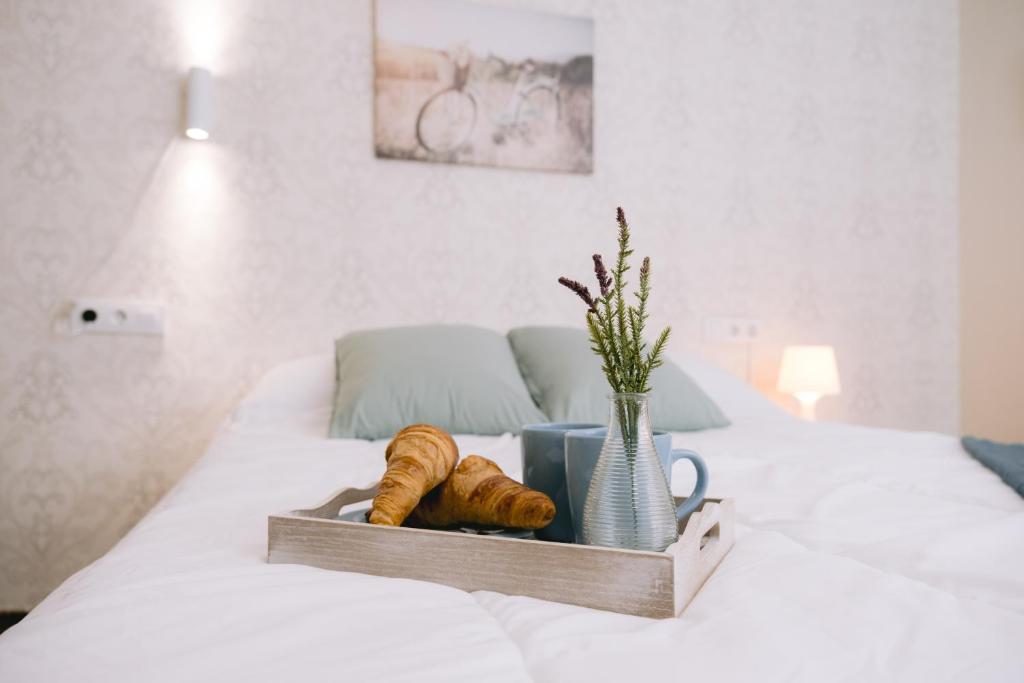 een dienblad met croissants en een vaas op een bed bij Piso compartido Delyrent, Reja in Jaén