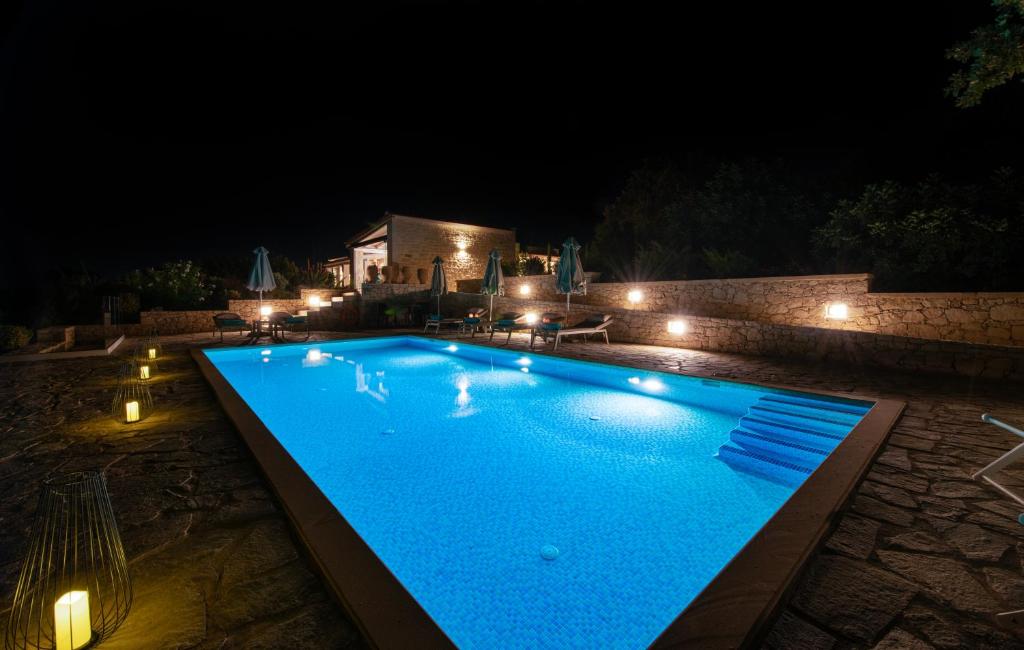 a large blue swimming pool at night with lights at Villa PanSara Exclusive Luxury in Metochia Fratzeskiana