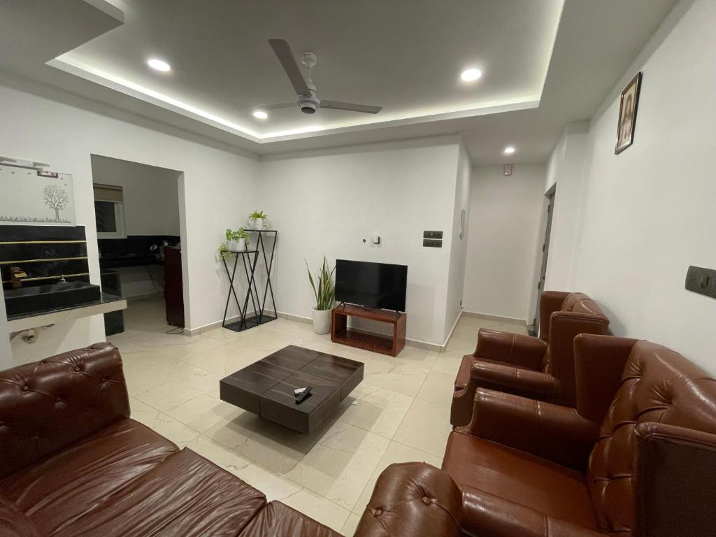a living room with brown leather furniture and a flat screen tv at BMRAN Luxury serviced apartment in Cochin