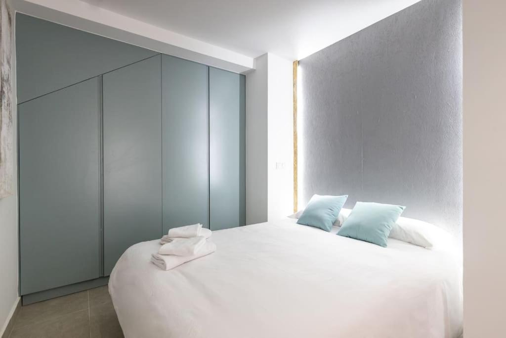 um quarto com uma grande cama branca com almofadas azuis em Estudio moderno y acogedor en Madrid Rio nº4 em Madri