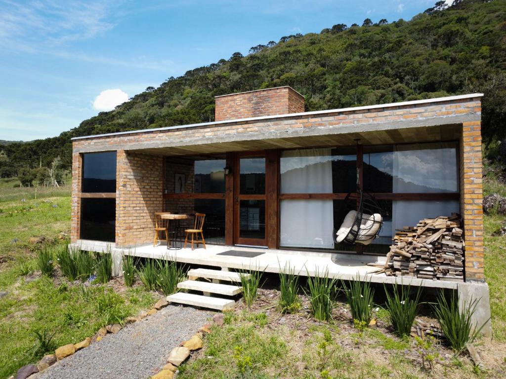 a small brick house with glass windows and a table at Chalé Monte Sião in Urubici