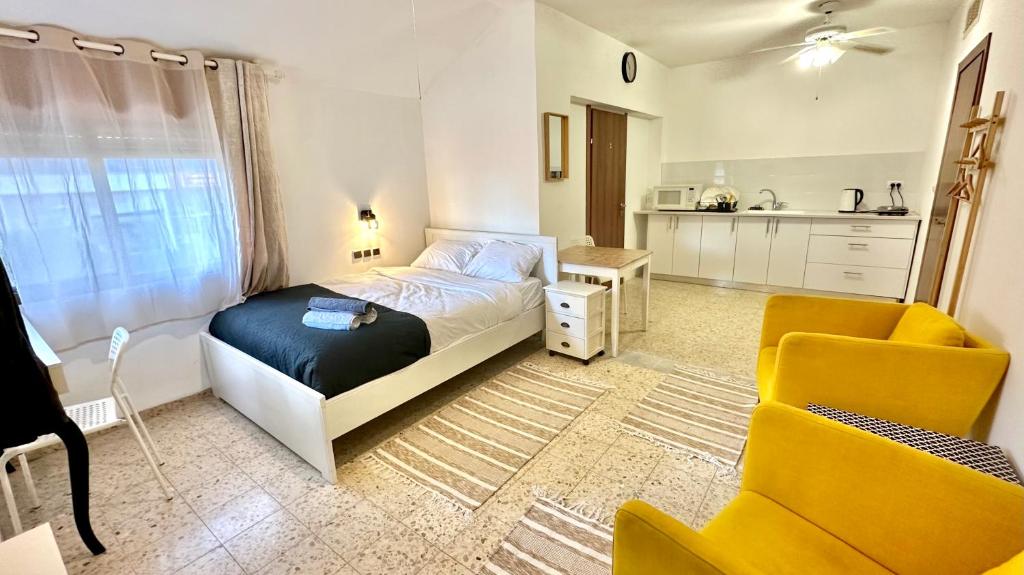 una camera con letto e sedia gialla di Salamandra Guest House a Nahariyya