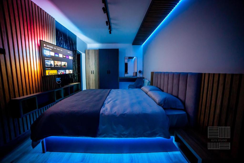 1 dormitorio con 1 cama con iluminación azul en Elite Studio Apartament, en Câmpulung Moldovenesc