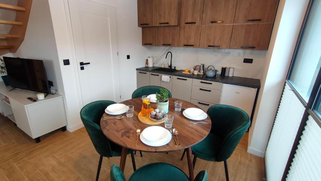 a small kitchen with a wooden table and green chairs at Balance Home in Tylicz