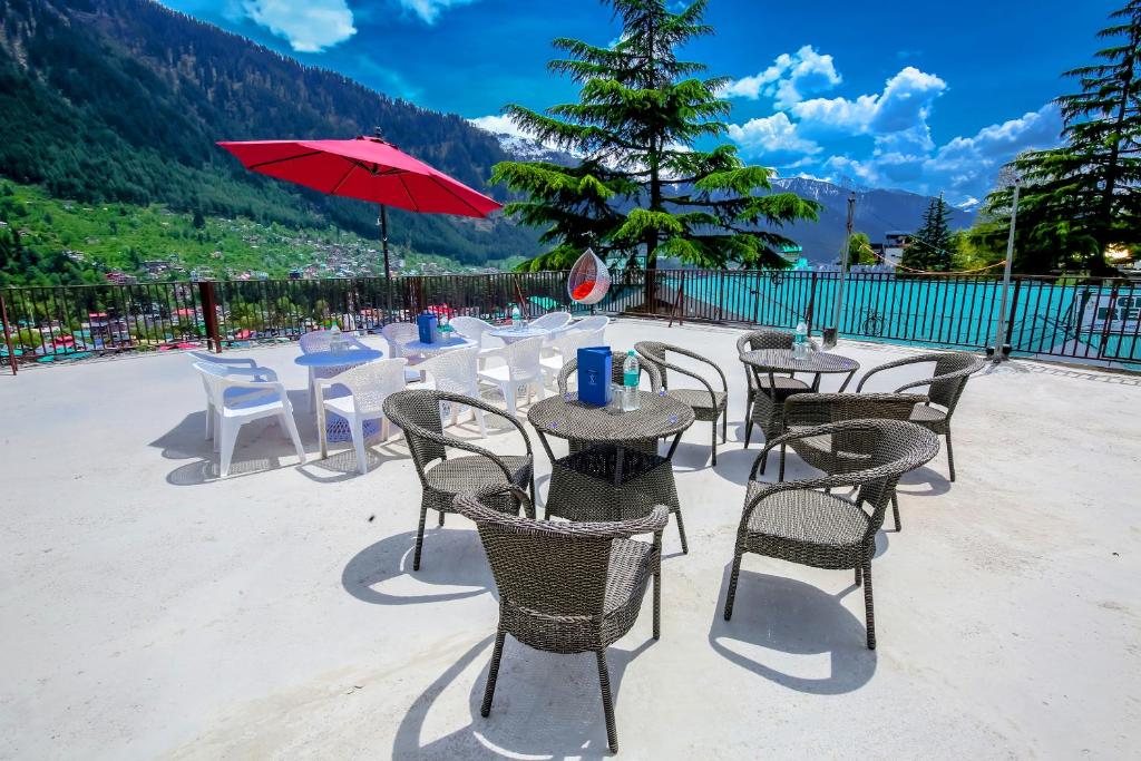 un patio con tavoli, sedie e ombrellone rosso di The Town House - Lavish & Luxury Rooms Near mall Road Manali a Manāli