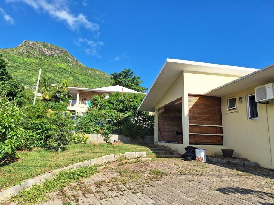 une maison blanche avec une colline en arrière-plan dans l'établissement Maison Tamarin - Riviere Noire pour 5 personnes, à Rivière Noire