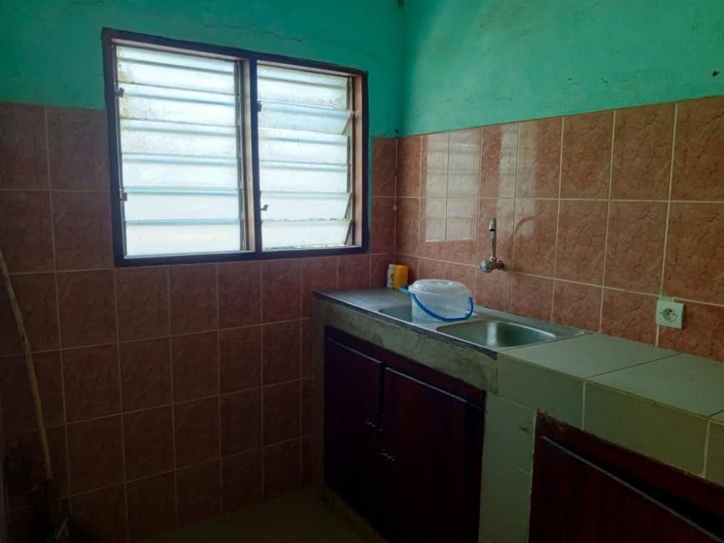 eine kleine Küche mit einem Waschbecken und einem Fenster in der Unterkunft Appat'Adjanohoun in Ouidah
