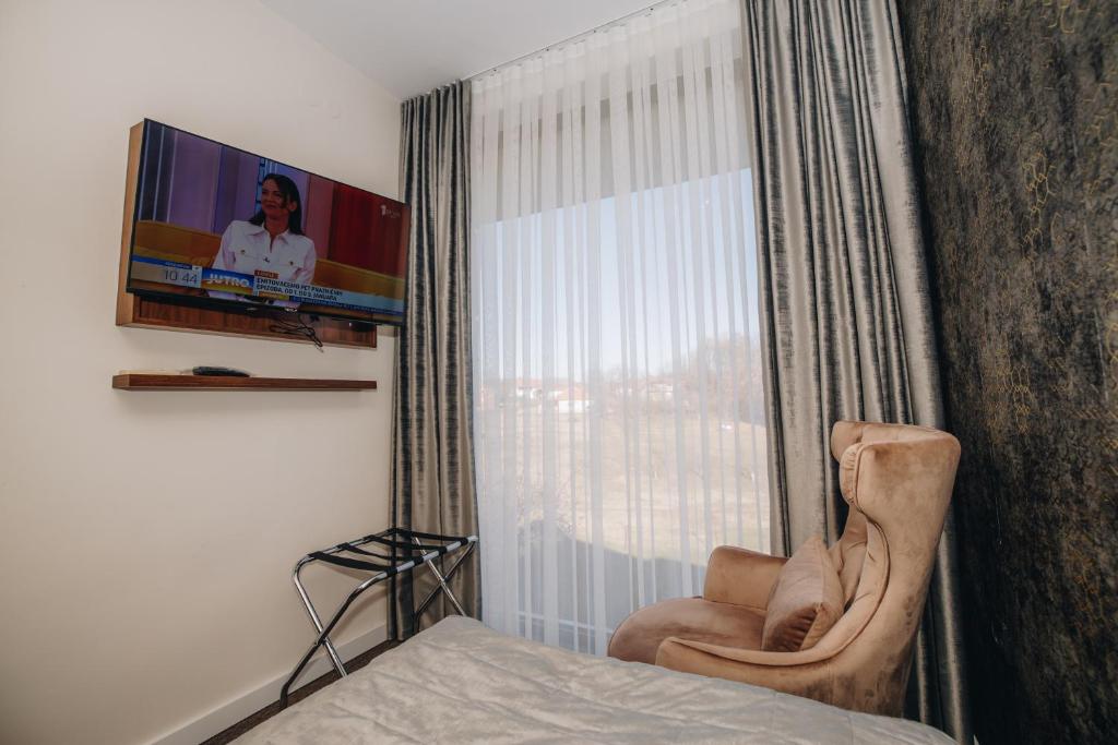 1 dormitorio con TV, silla y cama en Garni Hotel Radović en Kragujevac