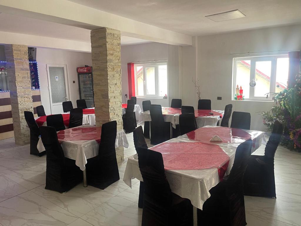 a dining room with tables and chairs with red and white table cloth at Pensiunea White House in Straja