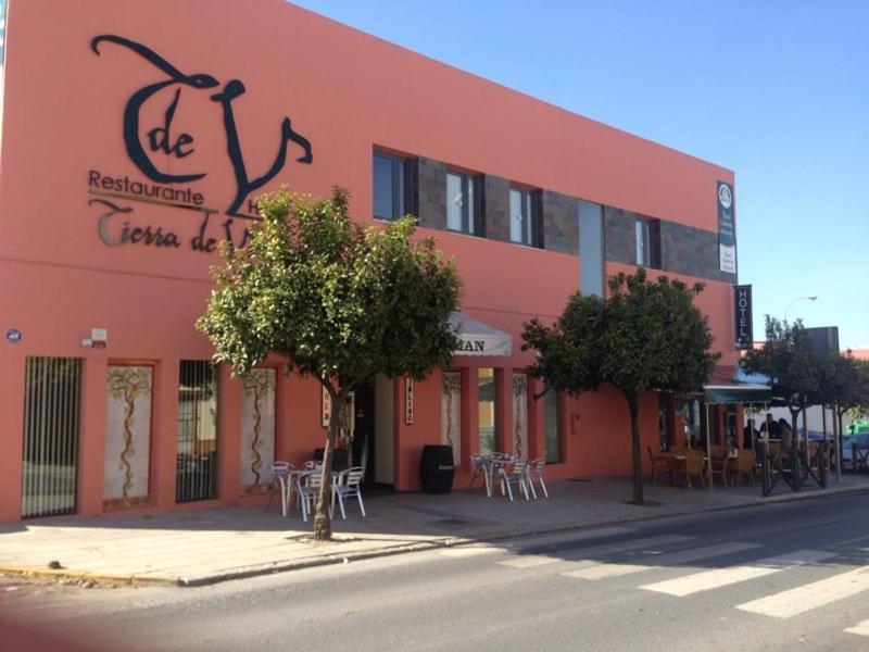 un edificio rojo con mesas y sillas delante de él en Hotel León Tierra de Vinos en La Palma del Condado