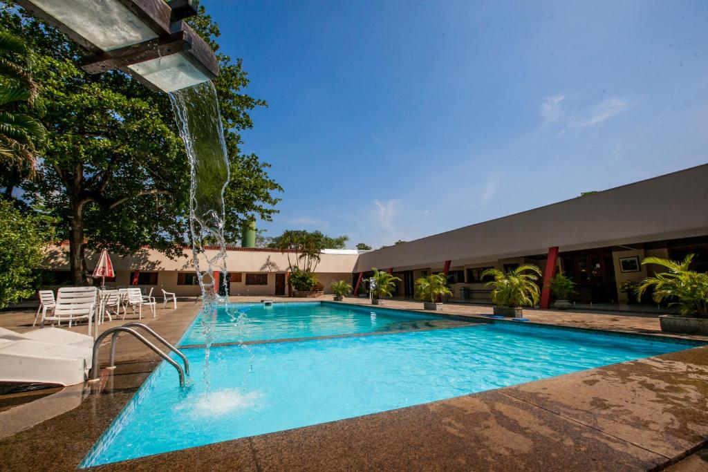 a swimming pool with a waterfall in a hotel at Hotel Fazenda Mato Grosso in Cuiabá