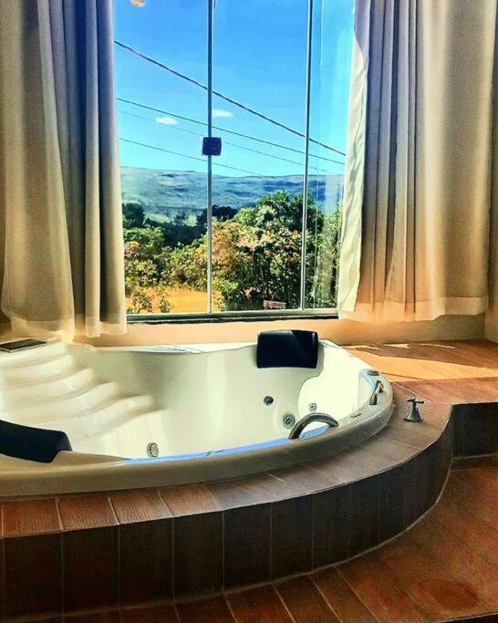 una vasca da bagno in una stanza con una grande finestra di Flat Safira com hidro - Chapada dos Veadeiros a Alto Paraíso de Goiás