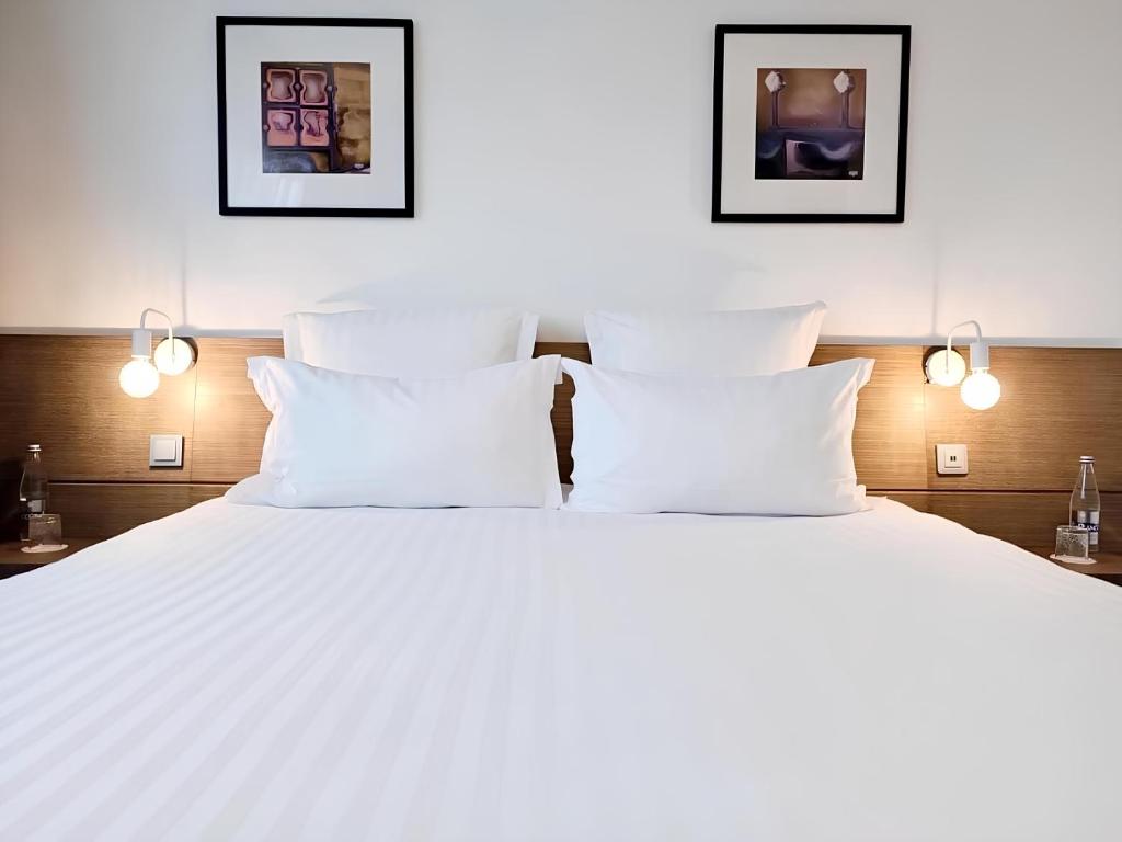 1 dormitorio con 1 cama grande con almohadas blancas en Best Western Hôtel De La Cité & Spa, en Guérande