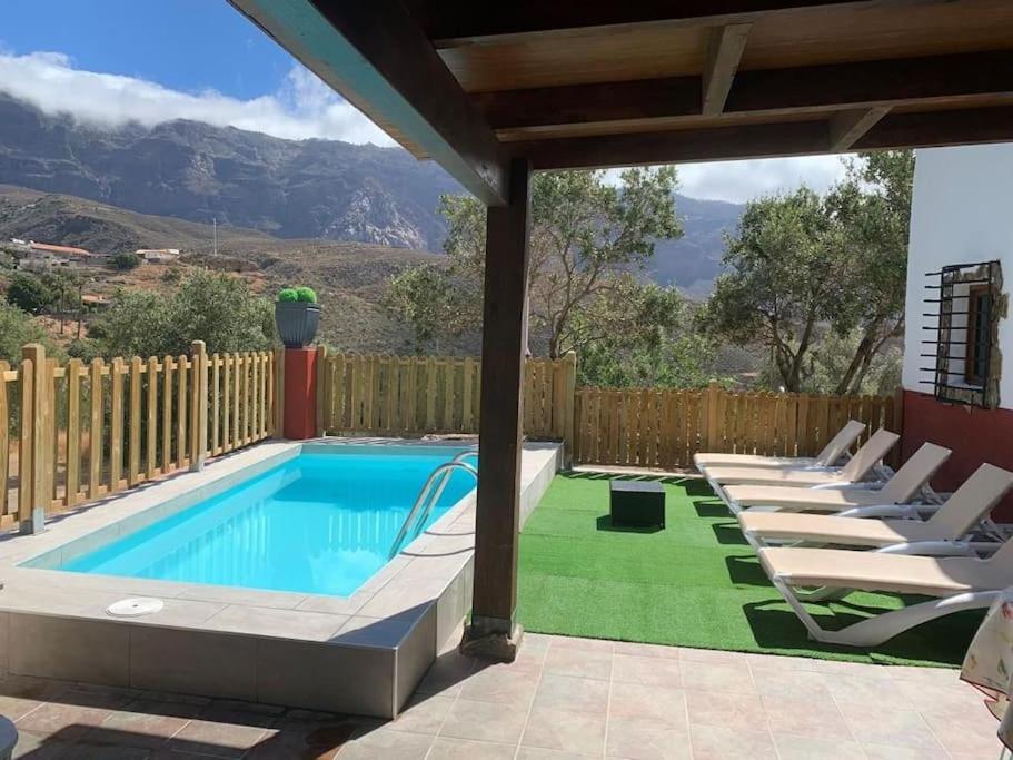 a swimming pool with lounge chairs next to a fence at La Casita Vibbecanarias Tunte in San Bartolomé