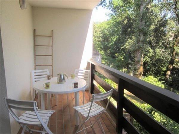 - un balcon avec une table et des chaises sur une terrasse couverte dans l'établissement Saint Georges de Didonne - BEL APPARTEMENT résidence boisée PROCHE MER, à Saint-Georges-de-Didonne