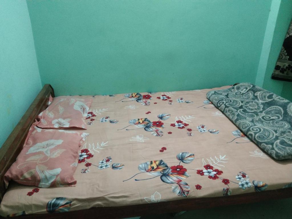 a bed with a comforter with flowers on it at New Milan Palace, DEOGHAR in Deoghar