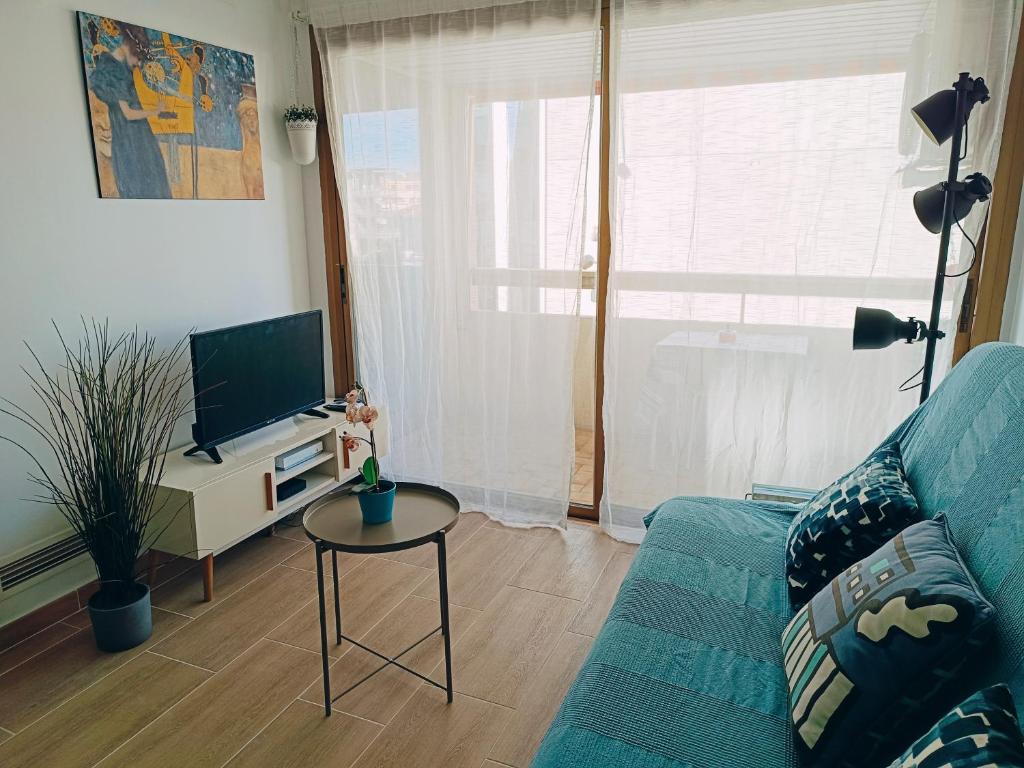 un salon avec un canapé bleu et une télévision dans l'établissement 2 pièces climatisé avec balcon dans le vieil Antibes, résidence avec ascenseur, à Antibes