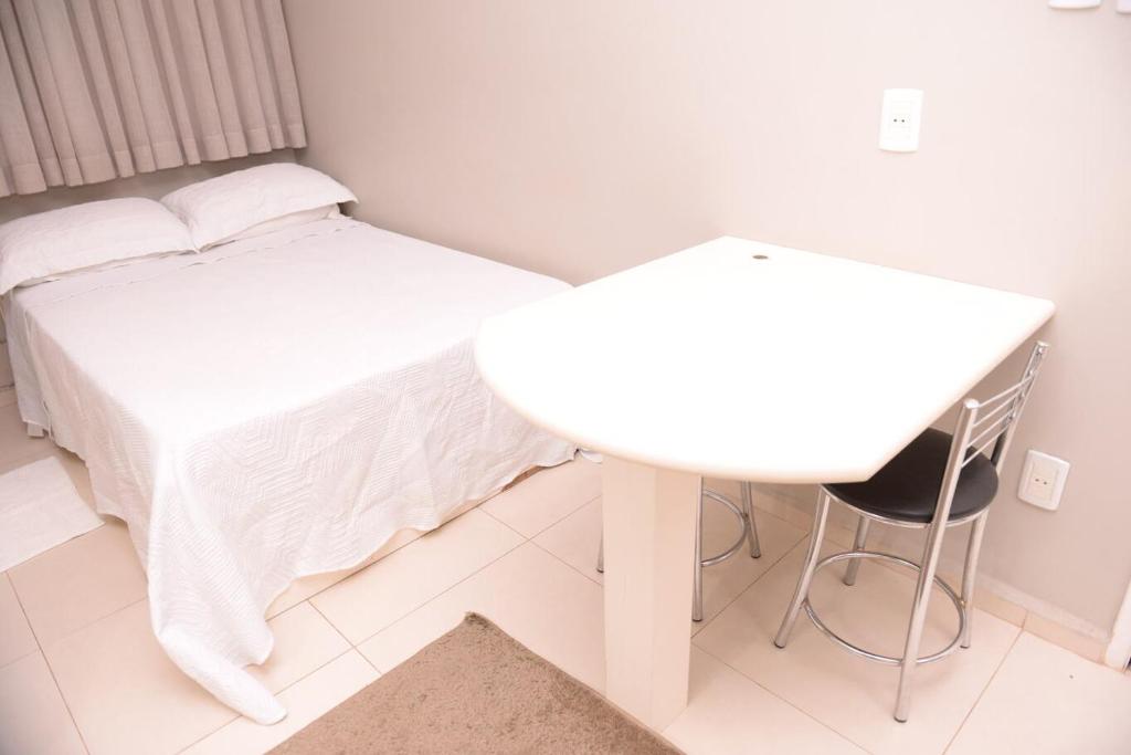 1 dormitorio con cama, mesa y escritorio en Otimo Flat c WI-FI no centro de Santa Rosa, en Santa Rosa