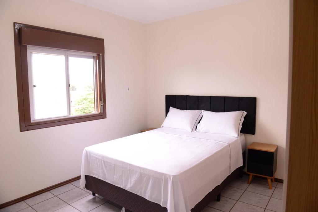 a bedroom with a large white bed with a window at Incrivel apto completo e confortavel Santa Rosa RS in Santa Rosa
