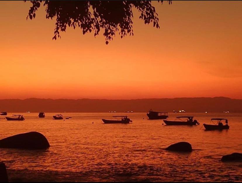 un grupo de barcos en el agua al atardecer en Casa Quintal - Pé na Areia - Araçatiba Ilha Grande, en Praia de Araçatiba