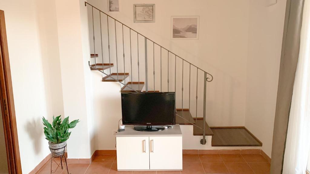 een tv bovenop een kast naast de trap bij Confortevole Appartamento con Piscina in Castiglione del Lago