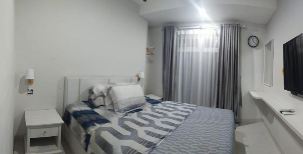 a small bedroom with a bed and a clock at Pentapolis Apartment in Balikpapan