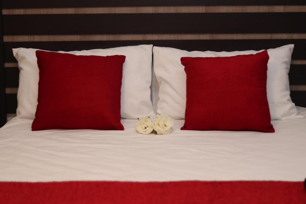 a bed with two red pillows and a stuffed animal on it at GLESTER GUEST HOUSE in Pretoria