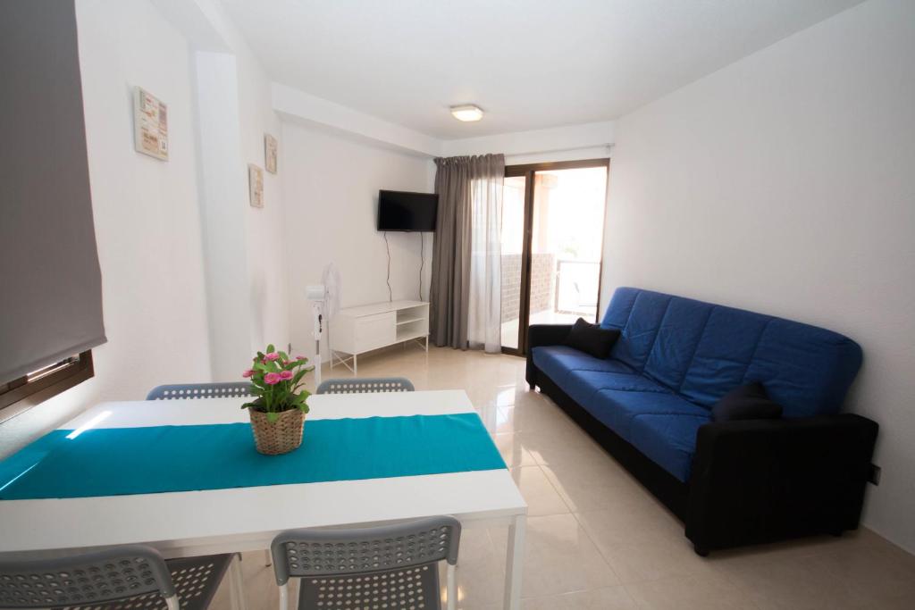 sala de estar con sofá azul y mesa en Apartamentos Maysan, en Benidorm