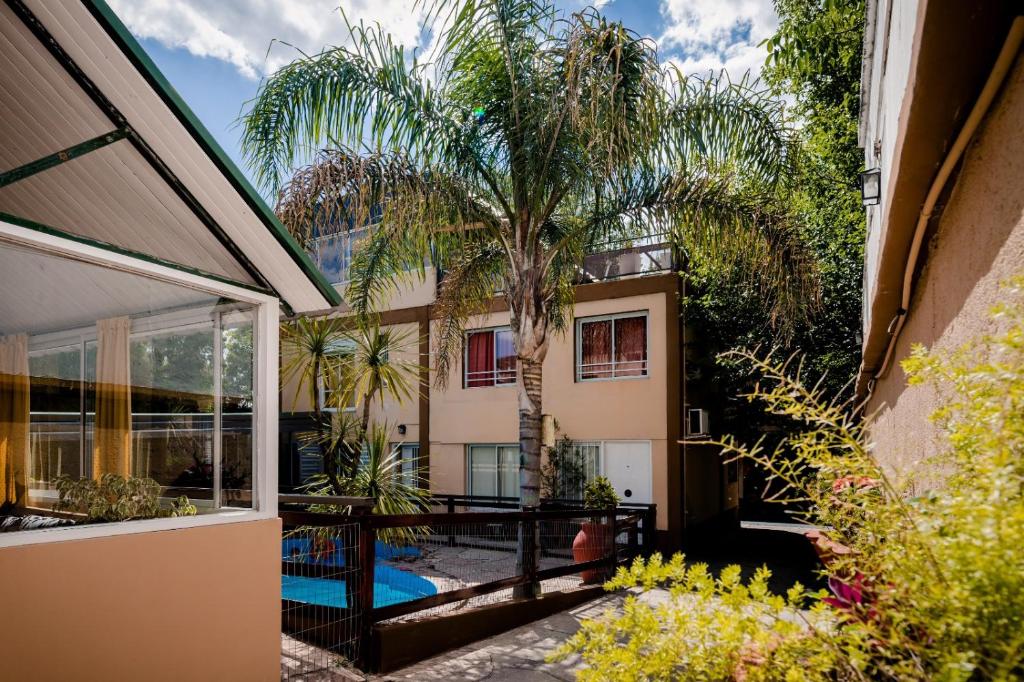 una vista exterior de una casa con una palmera en Carlos Paz Departamentos en Villa Carlos Paz