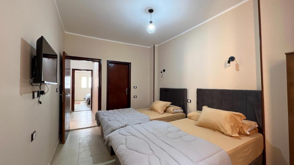 a bedroom with two beds and a flat screen tv at Pyramids Road in Cairo