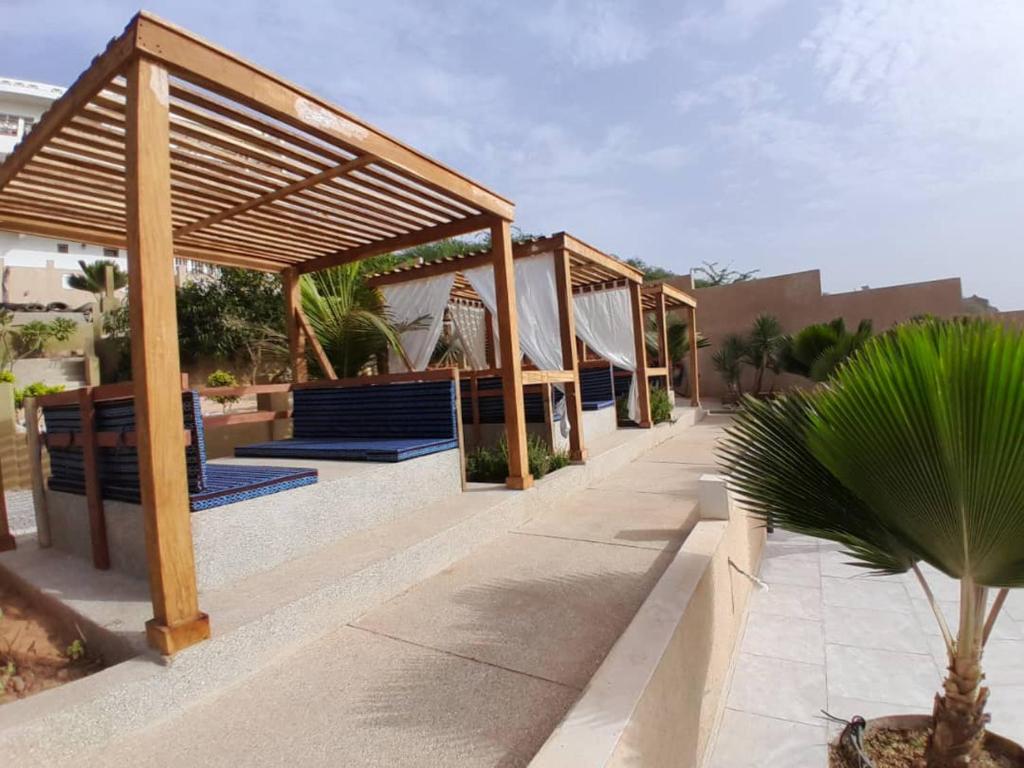 a pavilion with blue benches and a palm tree at La Villa d'O in Toubab Dialaw