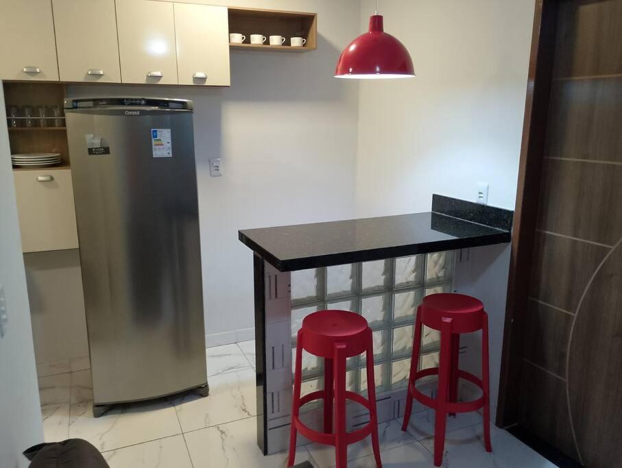 a kitchen with a counter and two red bar stools at Apartamento novo e confortável in Belém