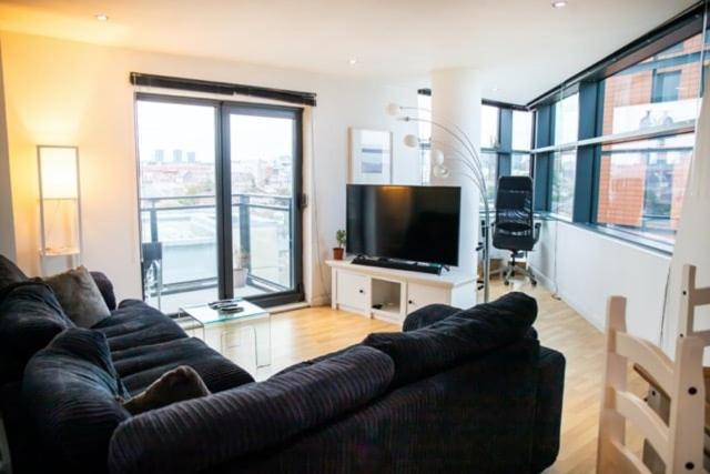 a living room with a couch and a flat screen tv at Modern 2-Bed Flat with Breathtaking City Views in Leeds