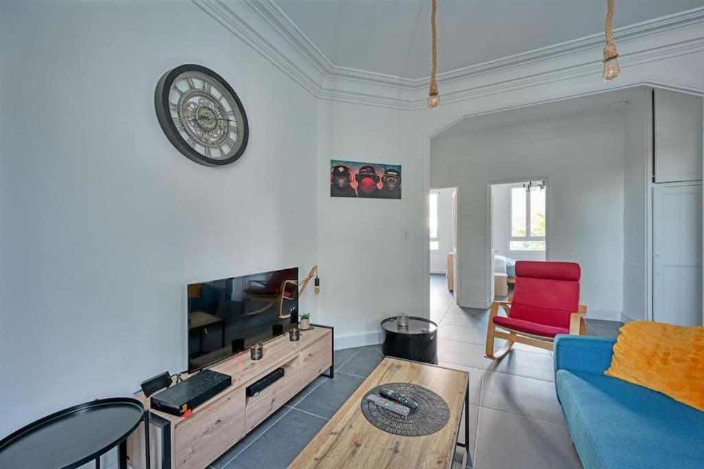 a living room with a blue couch and a clock on the wall at The Rooftop - AC CLIM - Wi-Fi - Parking gratuit dans la rue in Avignon